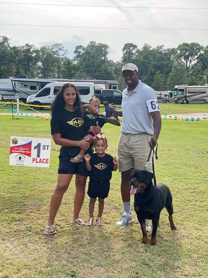 Honey with her handler and family beside a first-place sign at the National Sieger Show