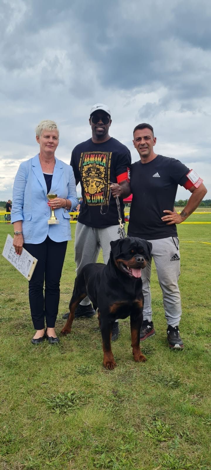 Uvo standing on lead with his handlers and the judge at a European show, the judge holding a trophy